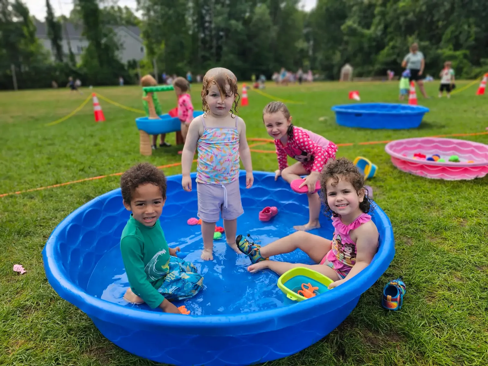 Young children playing in a wading pool on the grass at camp