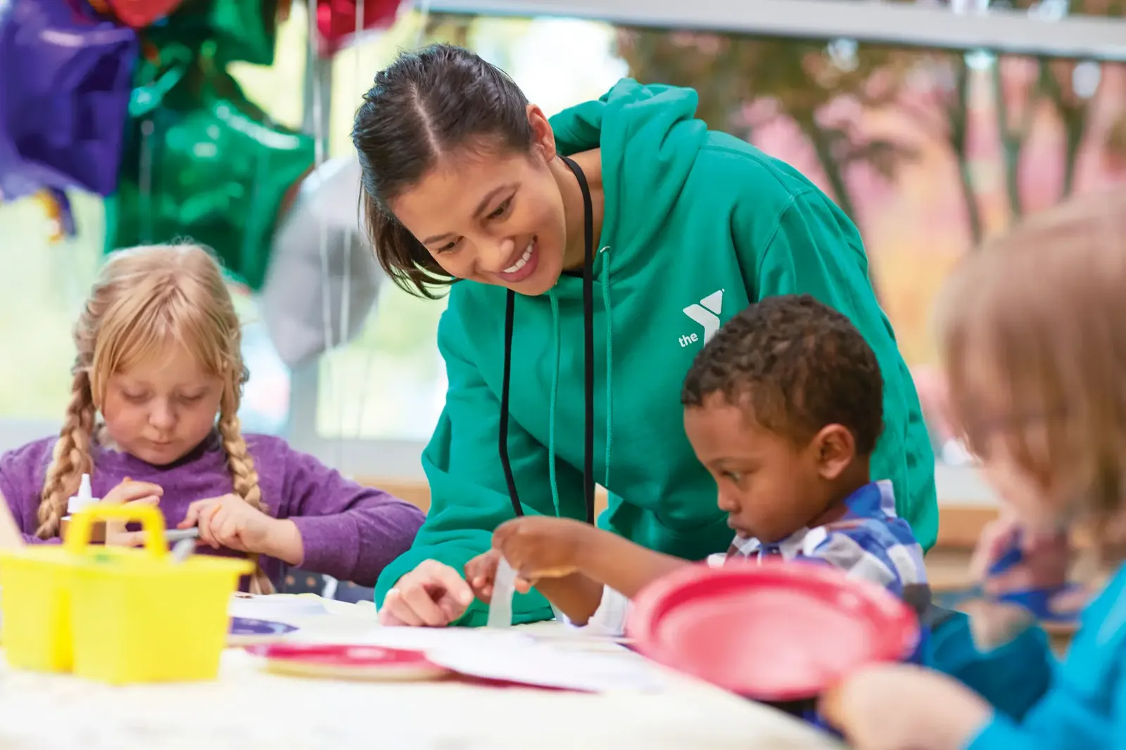 YMCA staff member helping kids with a craft at a birthday party
