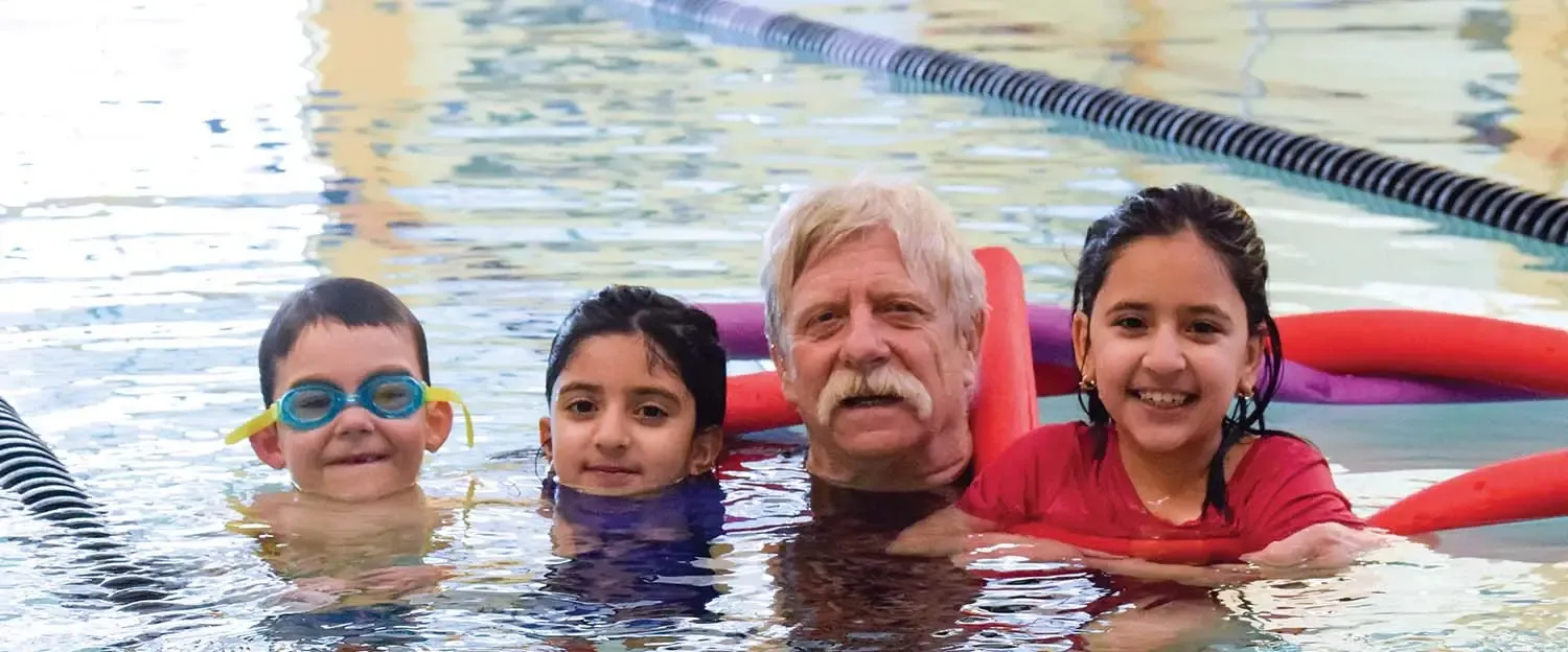Swimmers of all ages smiling together in the pool